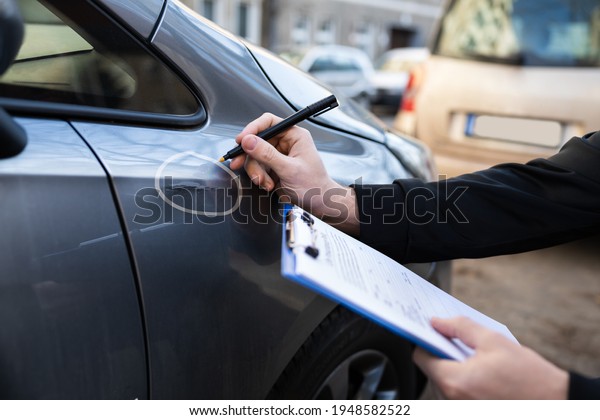 Insurance\
Agent Or Adjuster Inspecting Car After\
Accident