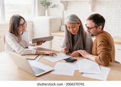 Insurance agent consulting mature family couple, discussing health insurance, signing contract deal of loan pension mortgage at home, calculating funds, investments, savings - Powered by Shutterstock