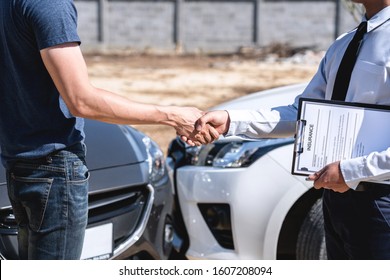 Insurance Agent and customer shaking hands after agreement about in insurance claim, assessed examining car crash, checking and signing on report claim form process after accident collision.