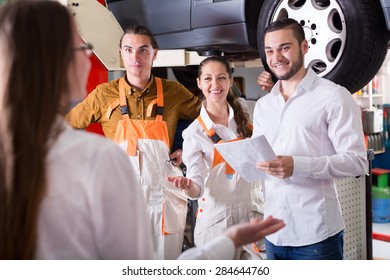 Insurance Agent Discussing With Mechanics Renewal Of A Car 