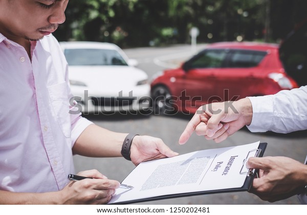 Insurance Agent examine Damaged Car and customer\
filing signature on Report Claim Form process after accident,\
Traffic Accident and insurance\
concept.