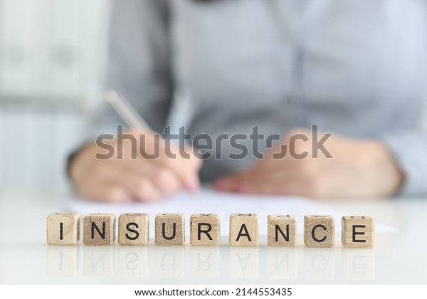 Insurance agent fills out insurance\
form in office. Medical and home insurance\
concept