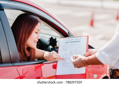 Insurance Agent Hand Over Car Insurance Document To Asian Woman Client In Car