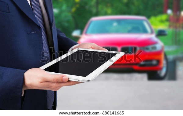 Insurance\
agent holding tablet and car on\
background