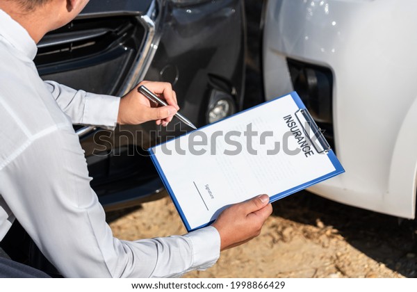 Insurance Agent Inspecting assessed Damaged\
Car checking and signing on report insurance claim form process\
after accident\
collision.