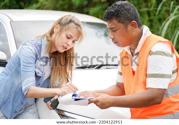 The insurance agent inspects the
damaged vehicle and The customer signs the filing of the
post-accident claim report form. Traffic accident and insurance
concept