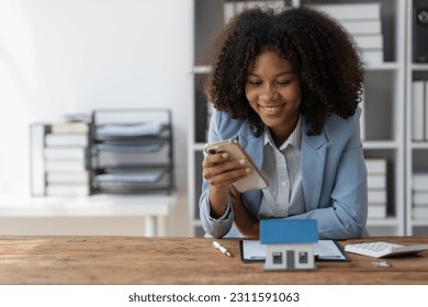 insurance agent, investor, american businesswoman Africans use their mobile phones to view information and connect with customers online. To contact to sign a lease, loan, buy a house, real estate. - Shutterstock ID 2311591063