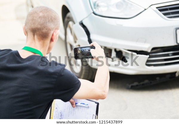 Insurance agent or loss adjuster inspecting\
damaged automobile