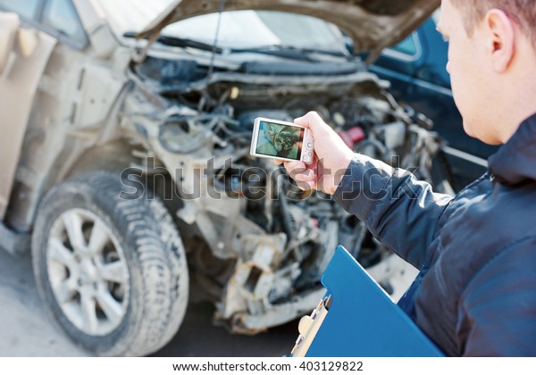 Insurance\
agent photographing car damage for claim\
form