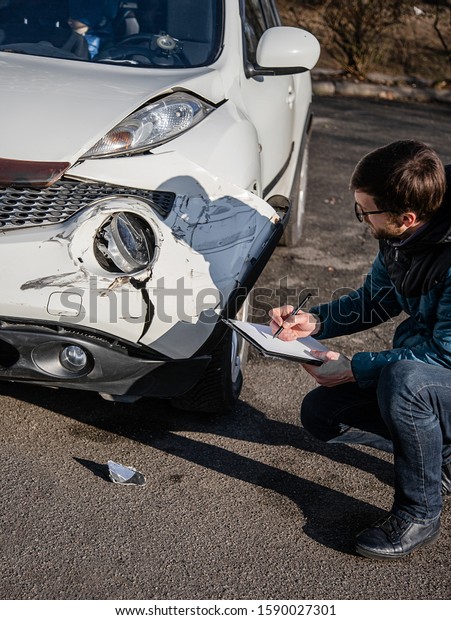 Insurance\
agent will examine and examine the damage to the car after an\
accident. Inspection of the car after an accident on the road. The\
front fender and right headlight are\
broken.