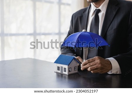 insurance business The agent spreads the umbrella on the house. The concept of preventing health accidents and natural disasters, a close-up image.