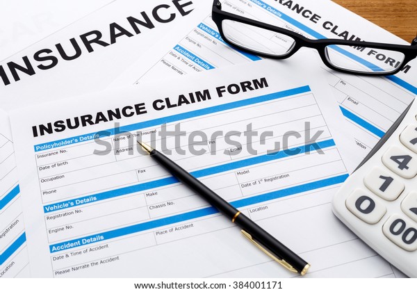 Insurance\
claim form with pen and calculator on wood\
desk