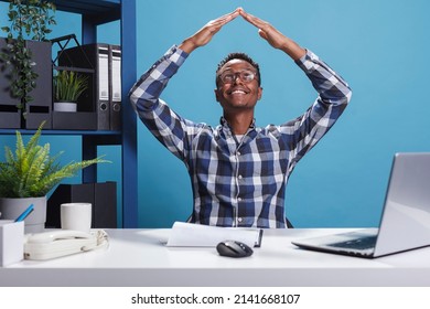 Insurance company office worker advertising safety symbol while recommending home protection. Agency employee doing roof gesture with arms while feeling safe and secure indoor.
