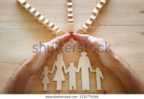 Insurance concept.\
Businessman protecting a family from domino effect. life, financial\
and health issues.