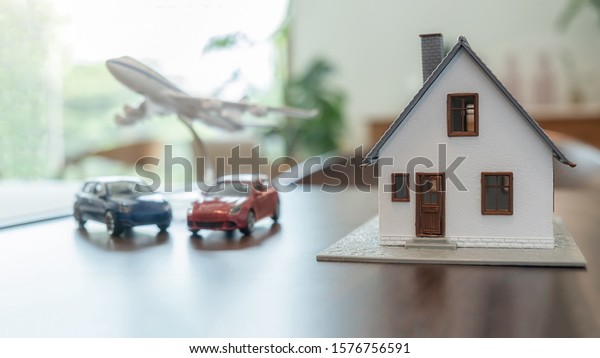 Insurance concept. House, Car and Airplane model\
on wooden table.