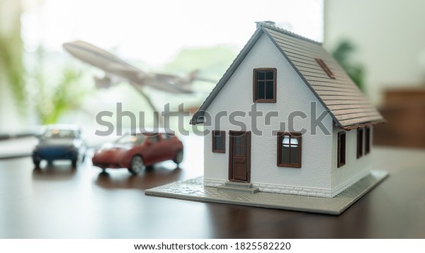 Insurance concept. House, Car and Airplane model\
on wooden table.