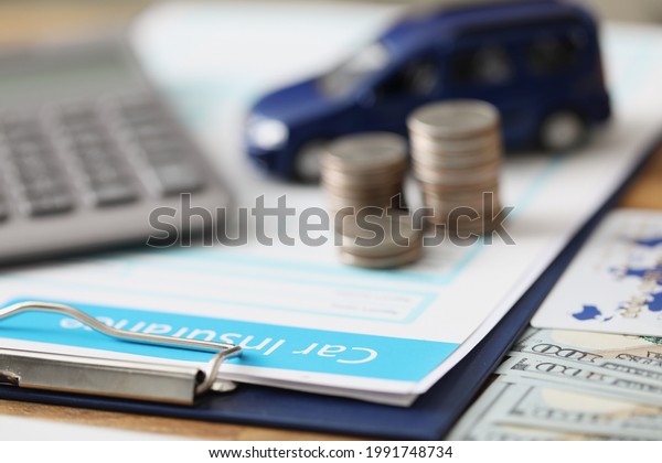 Insurance contract with coins and toy car together\
with calculator lie on\
table