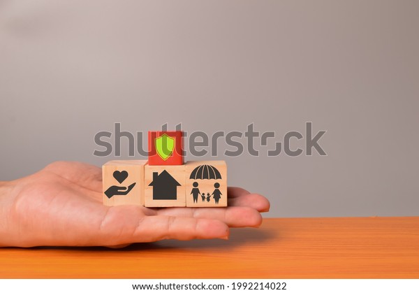Insurance coverage concept. Wooden blocks\
with shield, health, home and family\
icons