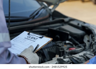 insurance form on clipboard held by mechanic with car engine. documentation process and client information collection in vehicle insurance claims. administrative aspect of automotive service - Powered by Shutterstock