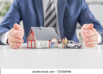 Insurance House, Car And Family Health Live Concept. The Insurance Agent Presents The Toys That Symbolize The Coverage.