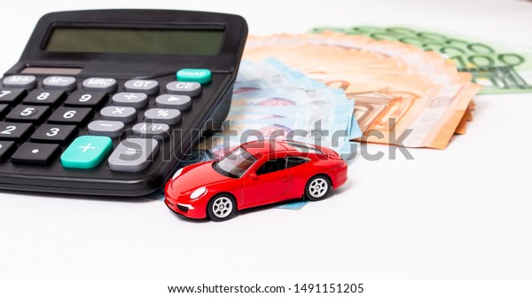 Insurance, loan and buying car concept. Red\
car and euro banknotes. Calculator, euro money and red car. Copy\
space for text. Calculatin cost of\
car.