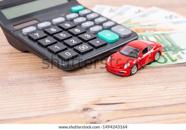 Insurance, loan and buying car concept. Red\
car and euro banknotes. Calculator, euro money and red car. Copy\
space for text. Calculatin cost of\
car.