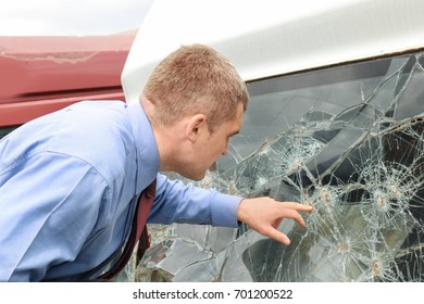 Insurance man checking broken windshield on car after accident