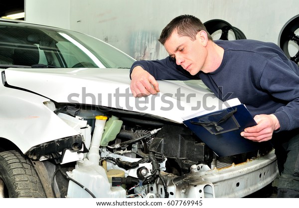 Insurance mechanic at\
work in car body\
shop.