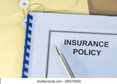 Insurance Policy Folder On Desk In Office With Pen And Manila Envelop