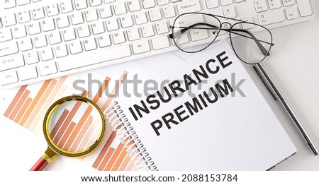 INSURANCE PREMIUM text written on notebook with keyboard, chart,and glasses