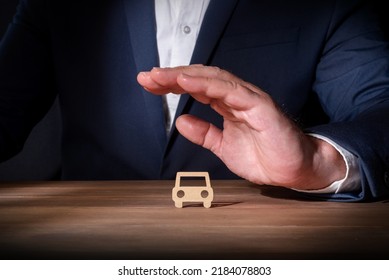 Insurance Professional Covering A Cardboard Cut-out Car With His Hand. Fully Comprehensive Vehicle Insurance. Protection Against Unforeseen Events On The Road