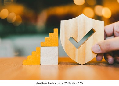 Insurance salesman holding shield symbol with wooden ladder step by step. Concept of insurance hierarchy with multiple levels from lowest to highest. - Powered by Shutterstock