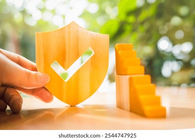 Insurance salesman holding shield symbol with wooden ladder step by step. Concept of insurance hierarchy with multiple levels from lowest to highest. - Powered by Shutterstock