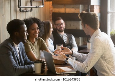 Insurance salesman or mortgage broker consulting young african american couple in cafe, caucasian realtor making offer explaining deal details to smiling black customers at meeting in coffee house