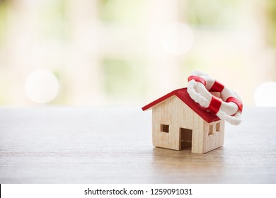 Insurance Services / Loan Debt Property House Protection Concept. Home On Red Lifebuoy Anchor On Wood Background. Strategy For Safe Secure Wealth From Risk Claims Real Estate