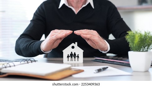 Insurer protecting a family and a house with his hands - Shutterstock ID 2253409363