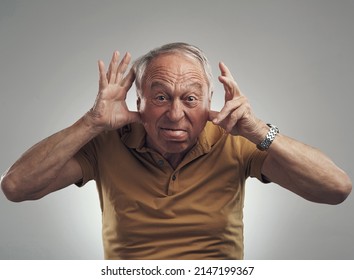 Int Ouch With My Inner Child. Studio Shot Of An Elderly Man Making A Funny Face Against A Grey Background.