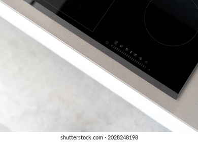 Integrated ceramic induction stove attached to kitchen counter, control panel with marked touch controls to easily adjust heat setting, modern kitchen appliances. Cropped shot
