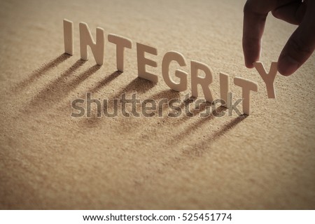 INTEGRITY wood word on compressed board with human's finger at Y letter