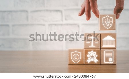 Intellectual property concept, Hand holding wooden block on desk with intellectual property icon on virtual screen.