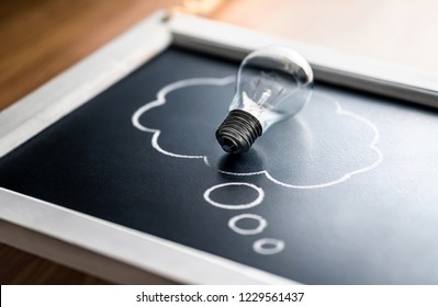 Intellectual property, new idea, psychology or brainstorm concept. Creativity, innovation and inspiration. Energy consumption. Light bulb on blackboard with thought bubble.
