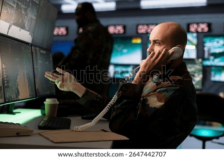 Intelligence corps specialist using communication systems to call in air strikes on enemy troops. Middle Eastern military dispatcher making phone call to request air support for ground soldiers