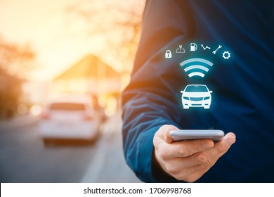 Intelligent Car App On Smart Phone Concept, Intelligent Vehicle And Smart Cars Concept. Person With Smart Phone On Street, Car In Background And Wireless Communication With Car.