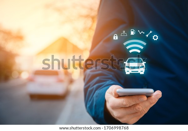Intelligent car app on\
smart phone concept, intelligent vehicle and smart cars concept.\
Person with smart phone on street, car in background and wireless\
communication with\
car.