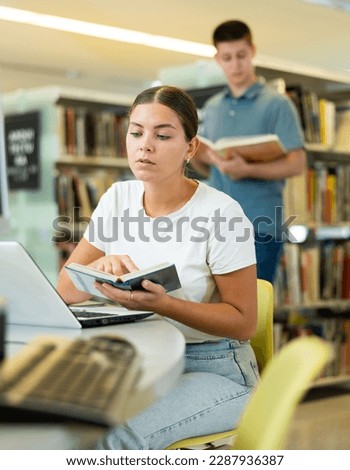 Intelligent Caucasian girl hold academic books in the college library..