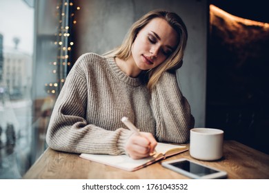 Intelligent Female Student Dressed In Casual Wear Writing Publication Text To Education Textbook, Creative Caucasian Woman Sitting At Cafeteria Table Using Notepad For Planning Organisation