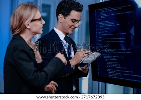 Intense code walkthrough. A female developer uses a stylus pointing to a specific line of code on the screen explaining its function to her male teammate during a debugging session.