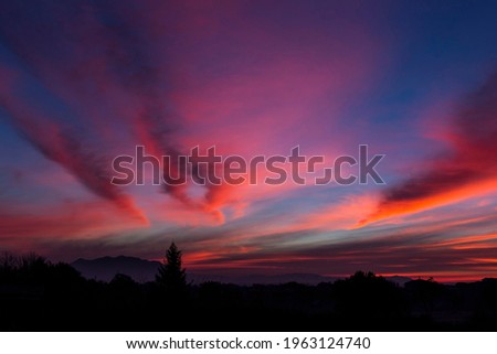 The intense colors of the dawn. The colored clouds cross the sky like flaming lines above the dark outline of Mount Soratte, in the Roman countryside.