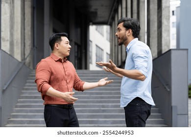 An intense exchange between two colleagues on office stairs captures a moment of workplace conflict. The image reflects emotions such as anger and stress, highlighting professional disagreements. - Powered by Shutterstock