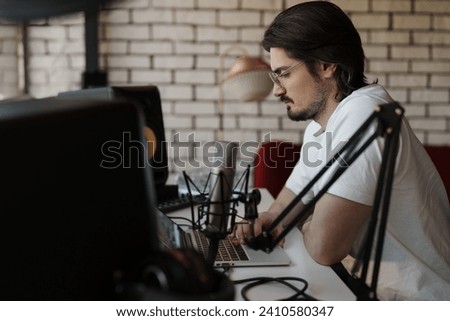 Intense focus as a sound engineer adjusts settings on a laptop in a studio with professional recording gear